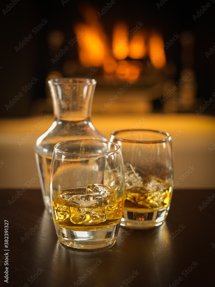 scotch whisky glassees with decanter and fire in background