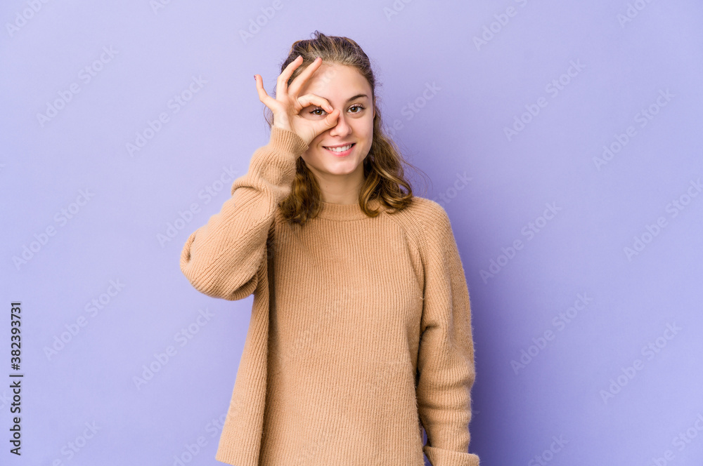 Fototapeta premium Young caucasian woman on purple background excited keeping ok gesture on eye.