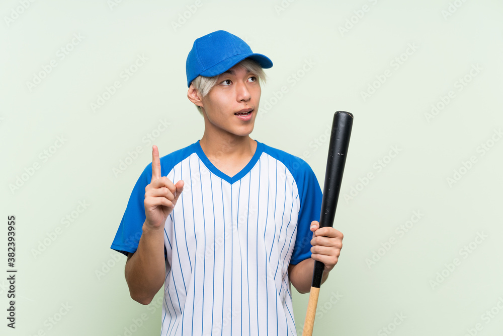 Young asian man playing baseball over isolated green background intending to realizes the solution while lifting a finger up Young asian man playing baseball over isolated green background intending to realizes the solution while lifting a finger up