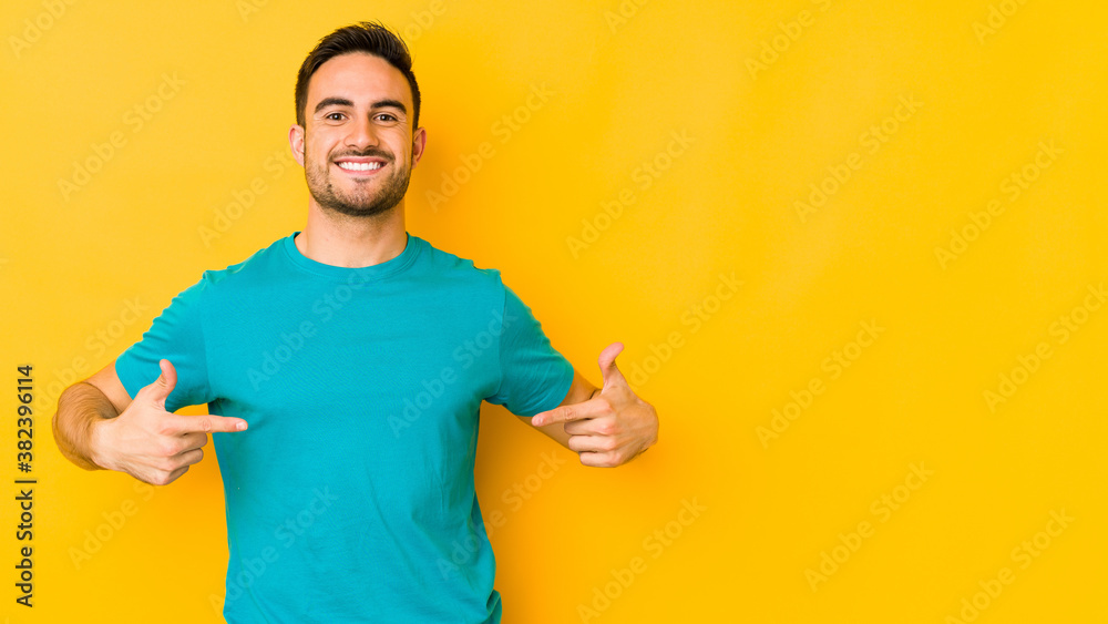 Young caucasian man isolated on yellow bakground points down with fingers, positive feeling. Young caucasian man isolated on yellow bakground points down with fingers, positive feeling.