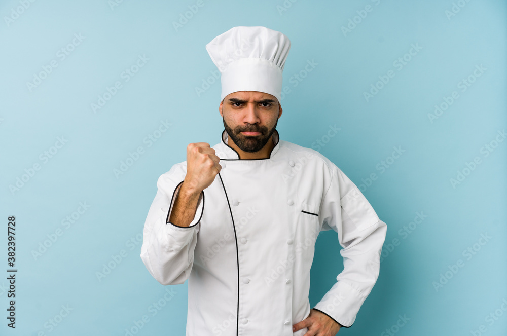 Young latin chef man isolated showing fist to camera, aggressive facial expression. Young latin chef man isolated showing fist to camera, aggressive facial expression.