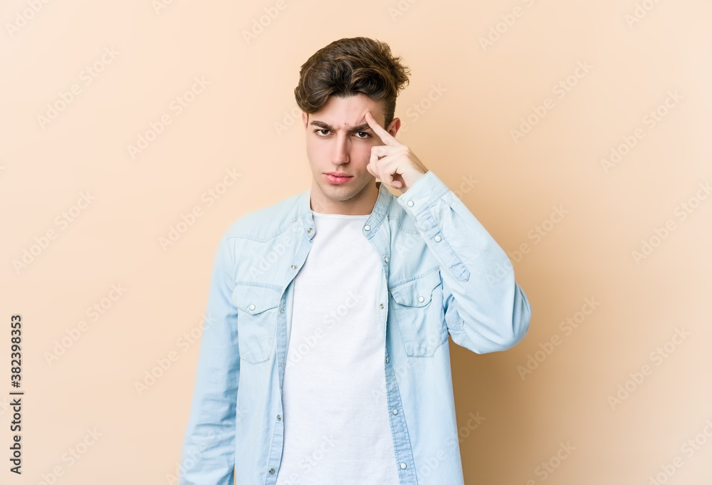 Young caucasian man isolated on beige background pointing temple with finger, thinking, focused on a task. Young caucasian man isolated on beige background pointing temple with finger, thinking, focused on a task.