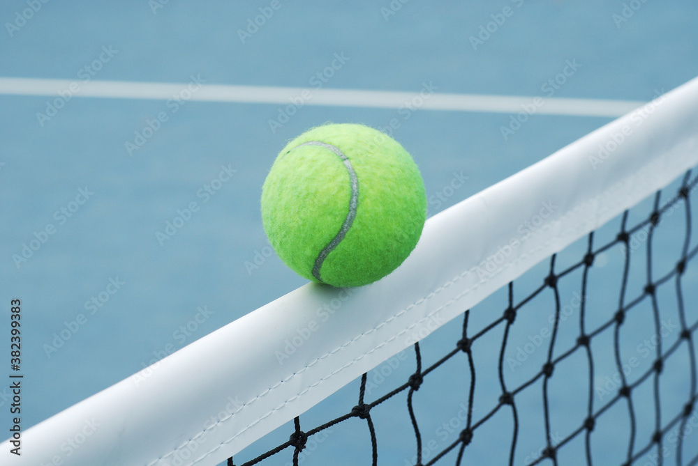Tennis ball on net  with concrete blue field and white line