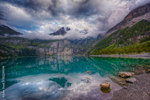 Fototapeta Naklejka Na Ścianę i Meble -  Soft evening light over the Swiss alps and lake on a cloudy day at Oschinensee Switzerland. It's a beautiful UNESCO heritage site with amazing landscapes and hiking trails. 

