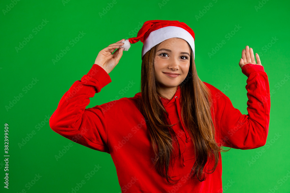 Young woman in red sweater and Christmas hat on green isolated background Young woman in red sweater and Christmas hat on green isolated background