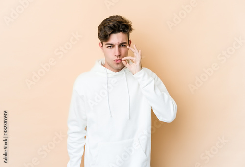 Young caucasian man isolated on beige background with fingers on lips keeping a secret.
