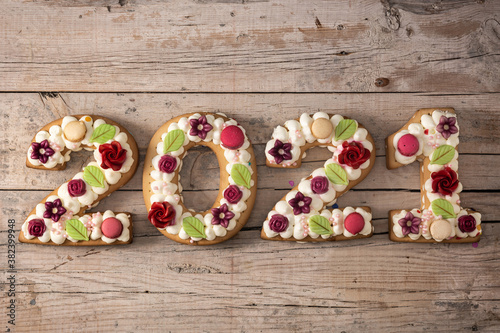 2021 cake decorated with flowers on wooden background. New year concept	
