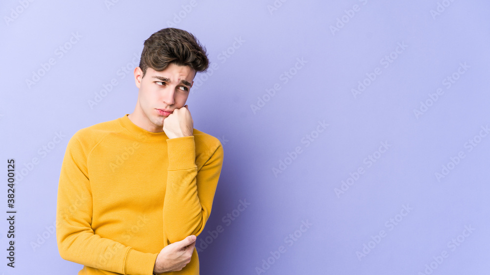 Young caucasian man isolated on purple background who feels sad and pensive, looking at copy space. Young caucasian man isolated on purple background who feels sad and pensive, looking at copy space.