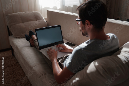 Fototapeta Naklejka Na Ścianę i Meble -  Remote Job. Man Working On Laptop Sitting On Sofa At Home.