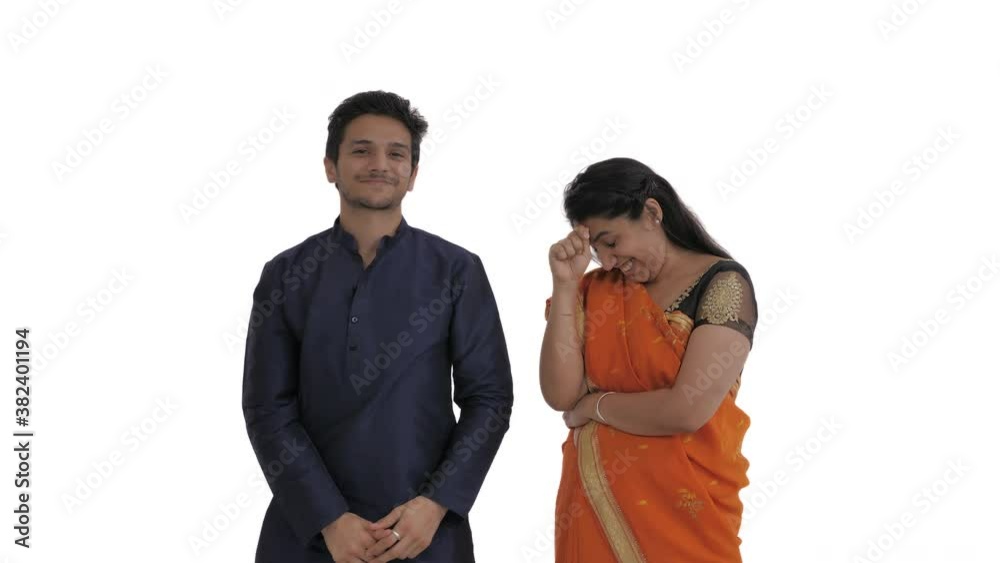 Portrait of young Indian couple. Man pretending hitting the ball with croquet mallet, asking his wife to let him go to the game. Woman expressing annoyance by gestures. Isolated on white background Portrait of young Indian couple. Man pretending hitting the ball with croquet mallet, asking his wife to let him go to the game. Woman expressing annoyance by gestures. Isolated on white background