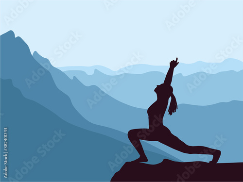 Silhouette of girl practising yoga. Blue mountains in background. Healthy lifestyle. © Anna