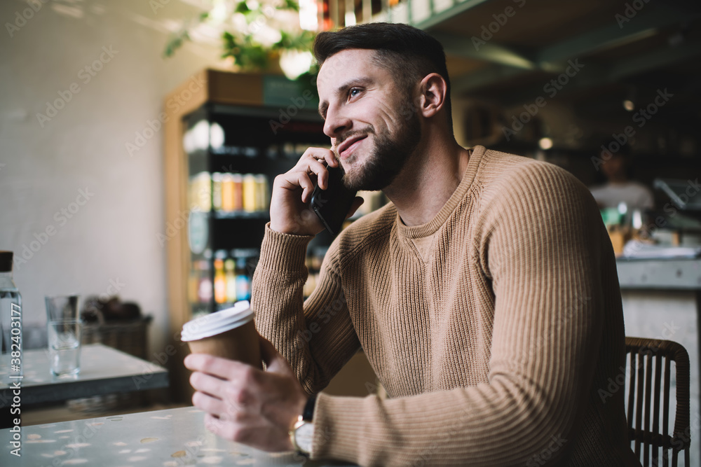 Cheerful man talking on smartphone at cafe