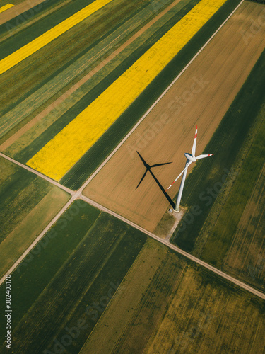 Aerial view of a wind turbine generator in green and yellow fields