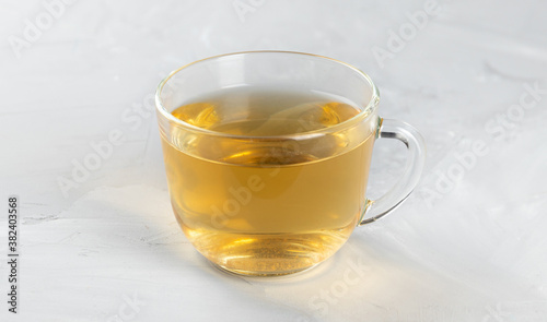 Green tea in a glass transparent cup with hot water on a concrete background