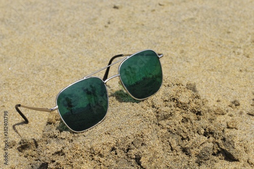 Reflecting sunglasses on a sandy beach in the summer, and the blue sky with people is reflected in glasses,