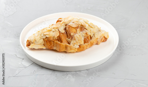 Baked fresh fragrant croissant with almonds, homemade baked goods on concrete background