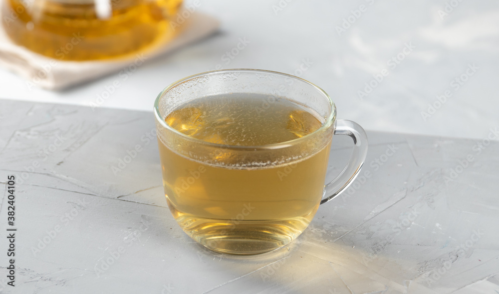 Green tea in a glass transparent cup with hot water on a concrete background