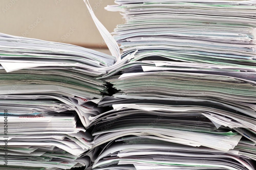 Office paperwork stacked haphazardly on a desk, closeup image. Overworked concept in business environment. Office paperwork stacked haphazardly on a desk, closeup image. Overworked concept in business environment.