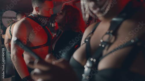 Close up of african female in sexy leather lingerie using smartphone