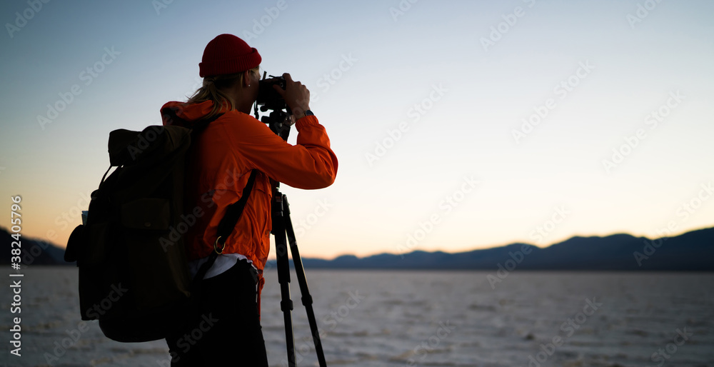 Fototapeta premium Unrecognizable female backpacker shooting mountains during sunset