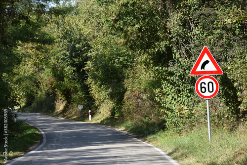 Road signs that shows maximum speed of 60 kilometers per hour and signa that warns drivers on sharp curve on the road ahead