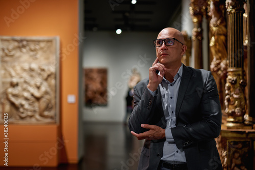 Portrait man looking at paintings standing in art gallery or museum, copy space