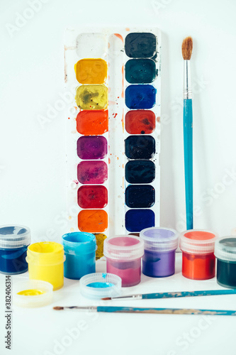 Colorful gouache paints and brush for painting on white background. Copy, empty space for text