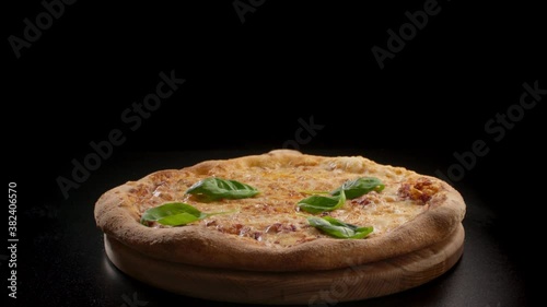 Fresh basil leaves falling on finished delicious margherita pizza. Black dark backgound