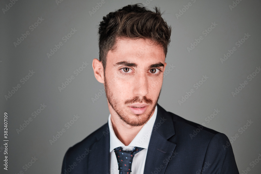 Young man close up portrait wearing a dark blue suit and a dark blue tie with red and light blue dots. Young man close up portrait wearing a dark blue suit and a dark blue tie with red and light blue dots.