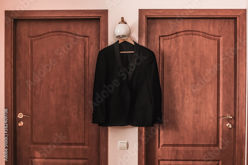 Men dark blue brown black formal classic blazer hanging. Brown wooden textured background 