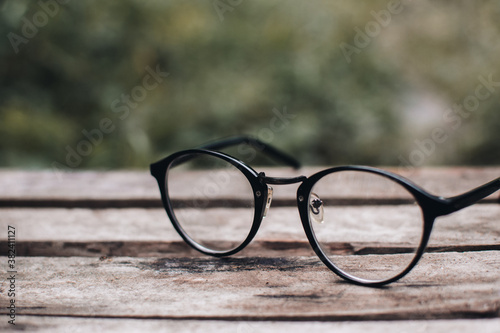 Hipster glasses on a park bench or table with a forest in the background