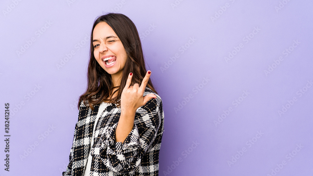 Young mixed race hispanic woman isolated showing rock gesture with fingers Young mixed race hispanic woman isolated showing rock gesture with fingers