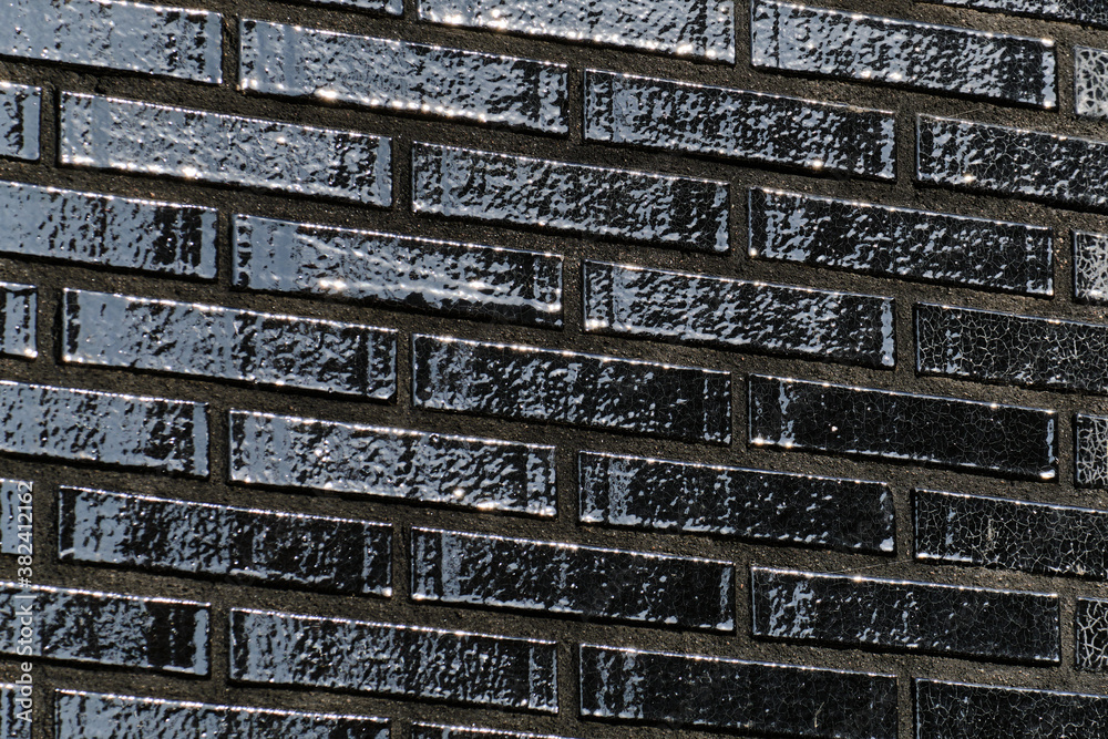The black glossy brick wall of a modern apartment building. Modern nordic architecture. Pattern of brick wall.
