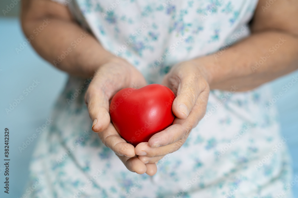 Asian senior or elderly old lady woman patient holding red heart in her hand on bed in nursing hospital ward, healthy strong medical concept Asian senior or elderly old lady woman patient holding red heart in her hand on bed in nursing hospital ward, healthy strong medical concept
