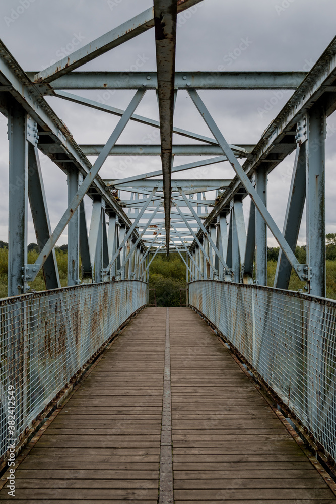Old metal foot bridge over river.