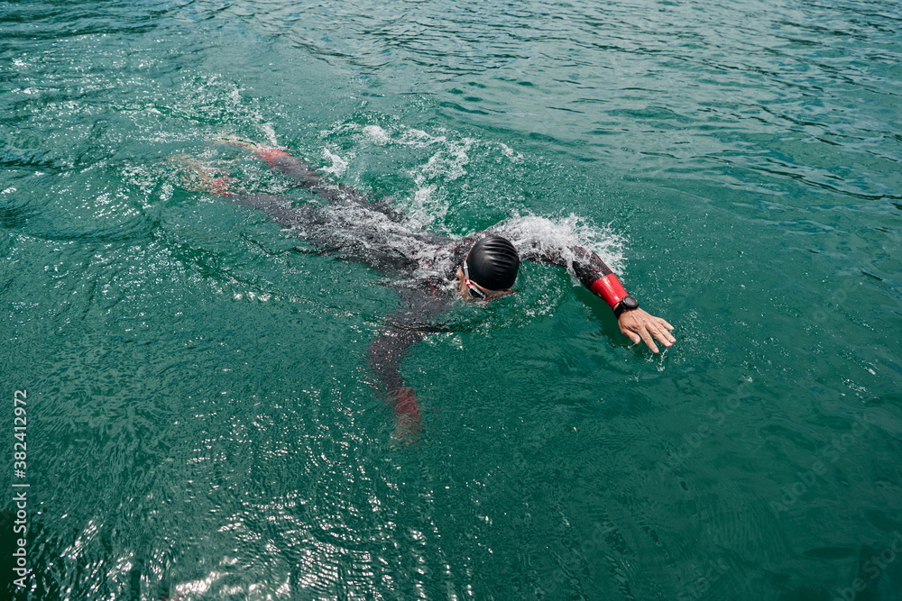 triathlon athlete swimming on lake wearing wetsuit