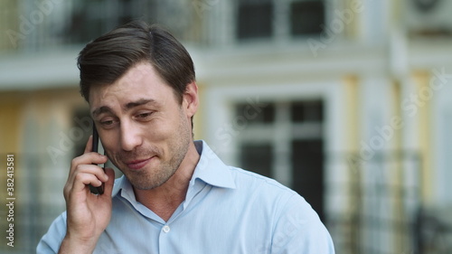Portrait man having phone talk outdoor. Man talking on phone in shirt outdoor