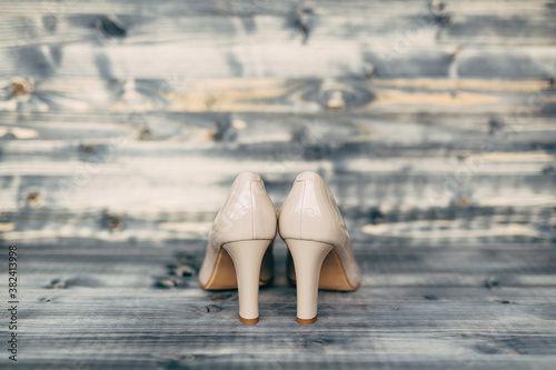 Beige high-heeled bridesmaid shoes on gray wooden texture.