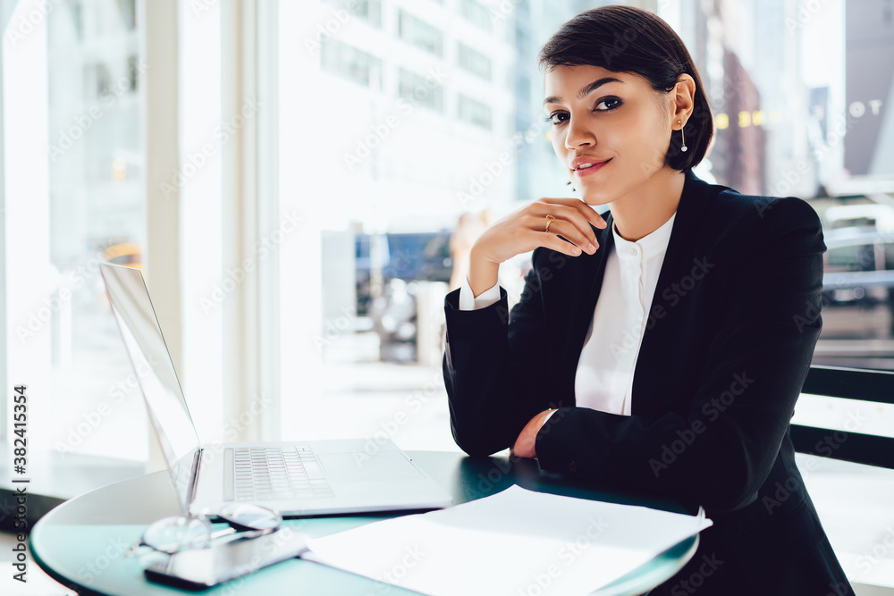 Positive woman sitting with computer and documents in office Positive woman sitting with computer and documents in office