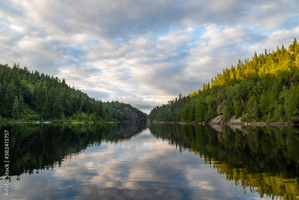 View of a peaceful lake with trees reflecting in the water in the Aiguebelle national park, Canada
