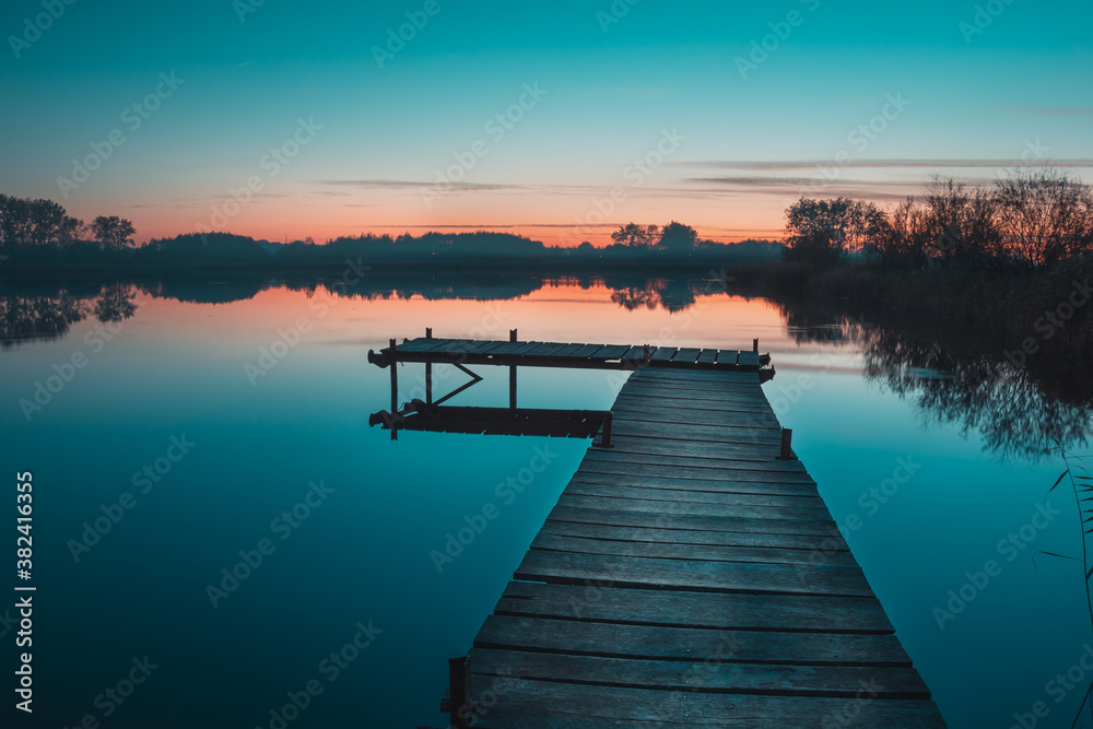 Wooden pier and a view of a calm lake after sunset