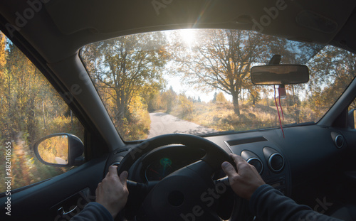 A man drives a car on a forest road in the autumn forest. Point of view.