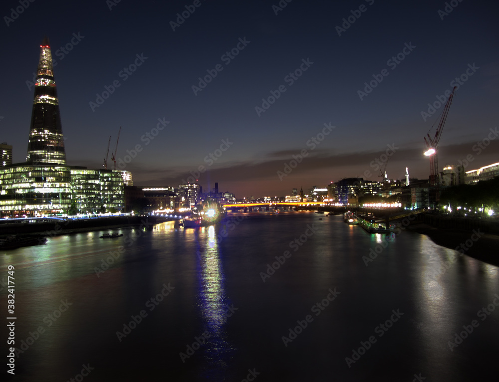 City skyline after sunset with the Shard, Southwark Bridge and Tower Bridge across Thames river with night lights in London, United Kingdom