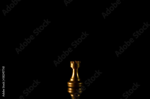 golden rook chess figures standing alone in the dark.