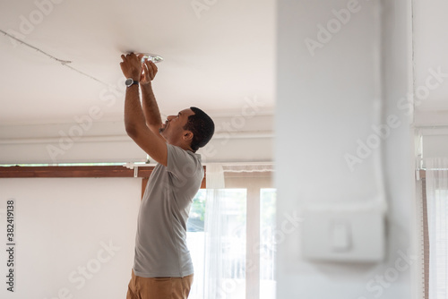 African American Man changing light bulb during COVID-19 quarantine at home photo