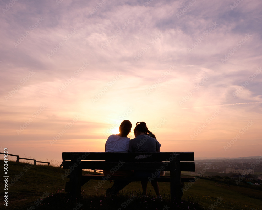silhouette of couple sitting on bench at sunset