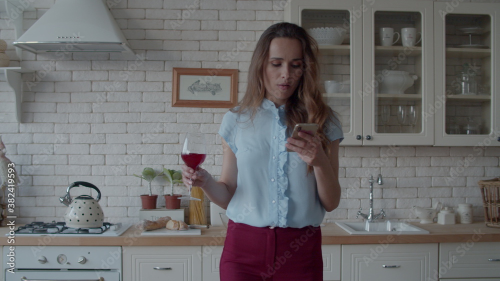 Attractive girl looking mobile phone with glass of wine at luxury kitchen. Attractive girl looking mobile phone with glass of wine at luxury kitchen.