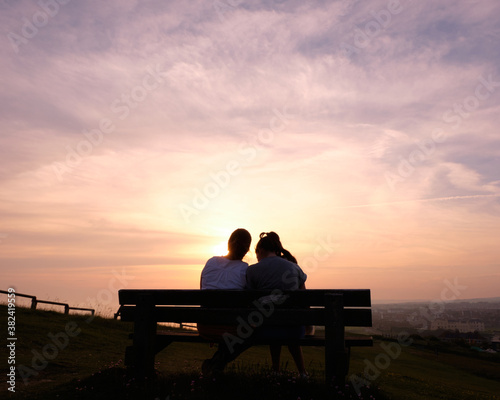 silhouette of couple sitting on bench at sunset