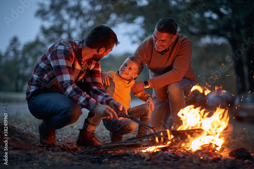 Grandfather, father and son camping together; Spring or autumn camping with campfire at night ; camping, travel, tourism, hike and people concept. Quality family time together.