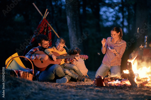 Family camping in the woods; Spring or autumn camping with campfire at night ; camping, travel, tourism, hike and people concept. Quality family time together.